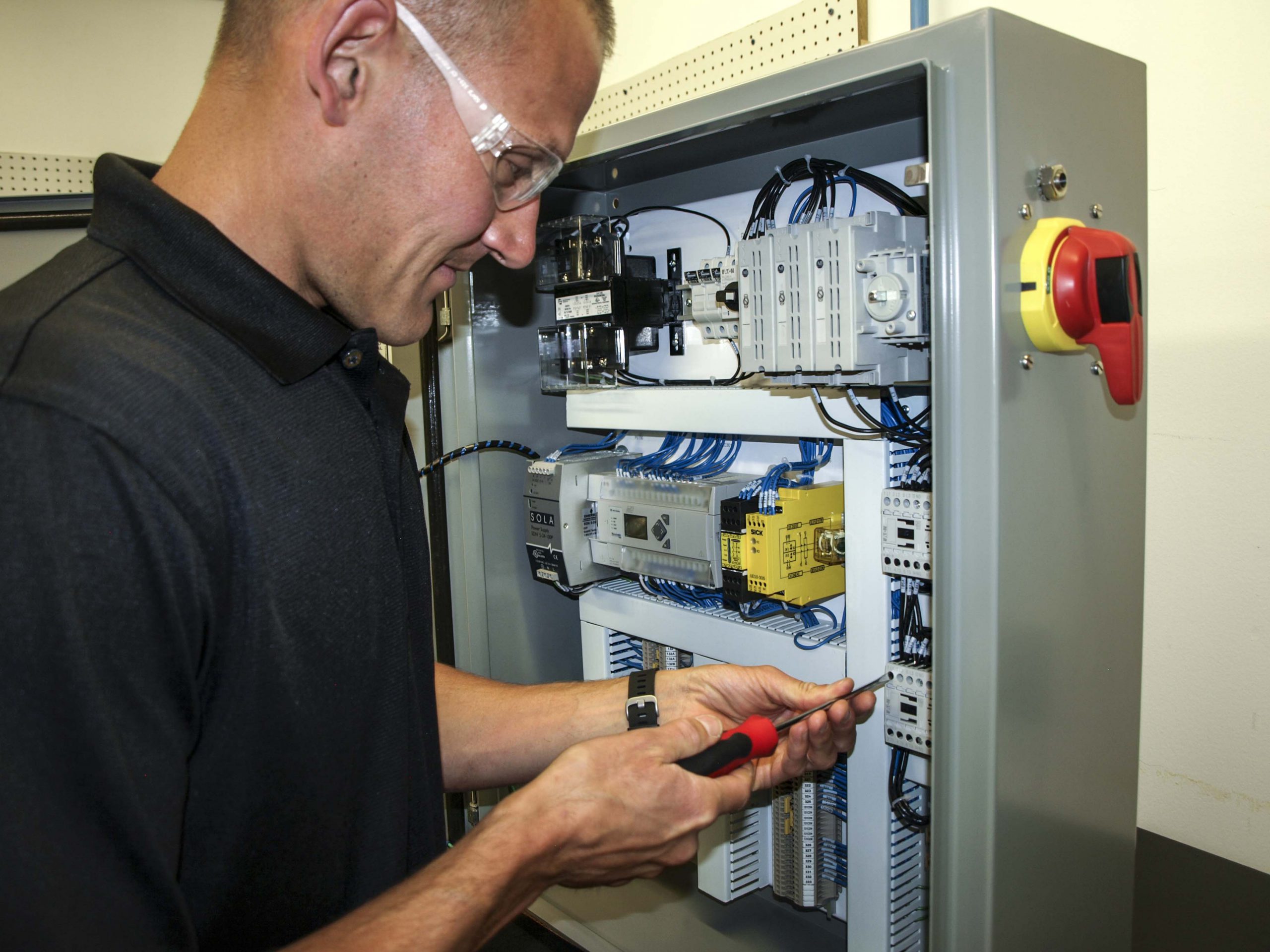 A JHFOSTER employee works on an electrical panel.